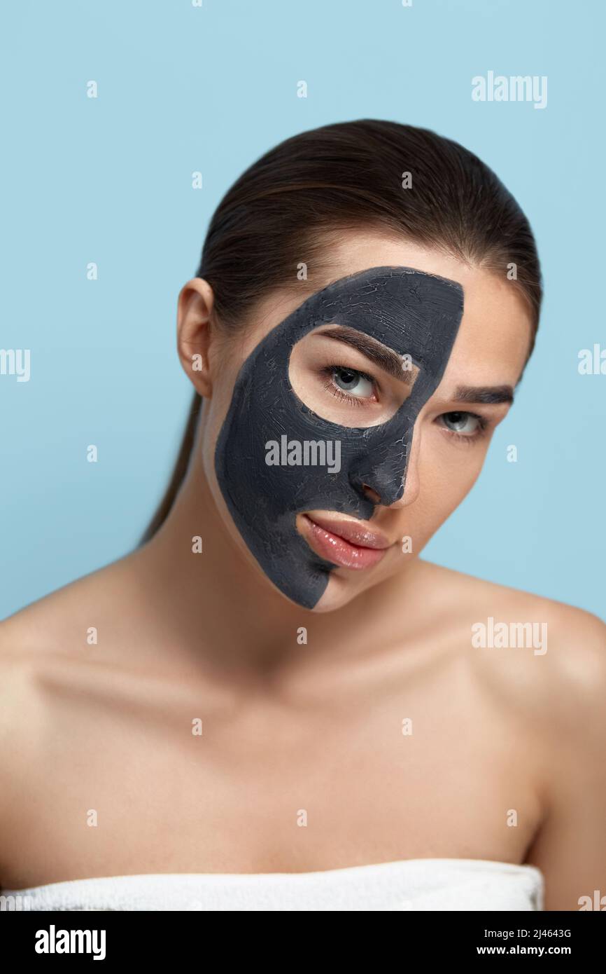 Portrait of a beautiful woman  with a black mask of clay on her face . Girl model beauty face with cosmetic mask . Skin care . Spa treatment. Cosmetol Stock Photo