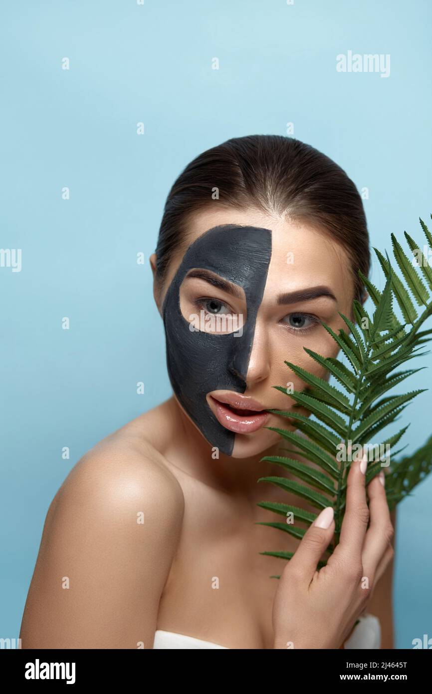 Beauty Woman Face Skin Care Mask. Portrait of a Beautiful Female with a Black Mask of Clay on Face .  Spa treatment . Girl Model with Moisturizer Cosm Stock Photo