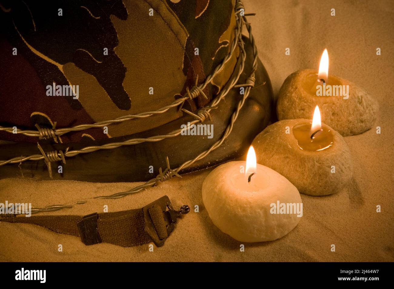 Helmet, barbed wire and candles in the sand Stock Photo