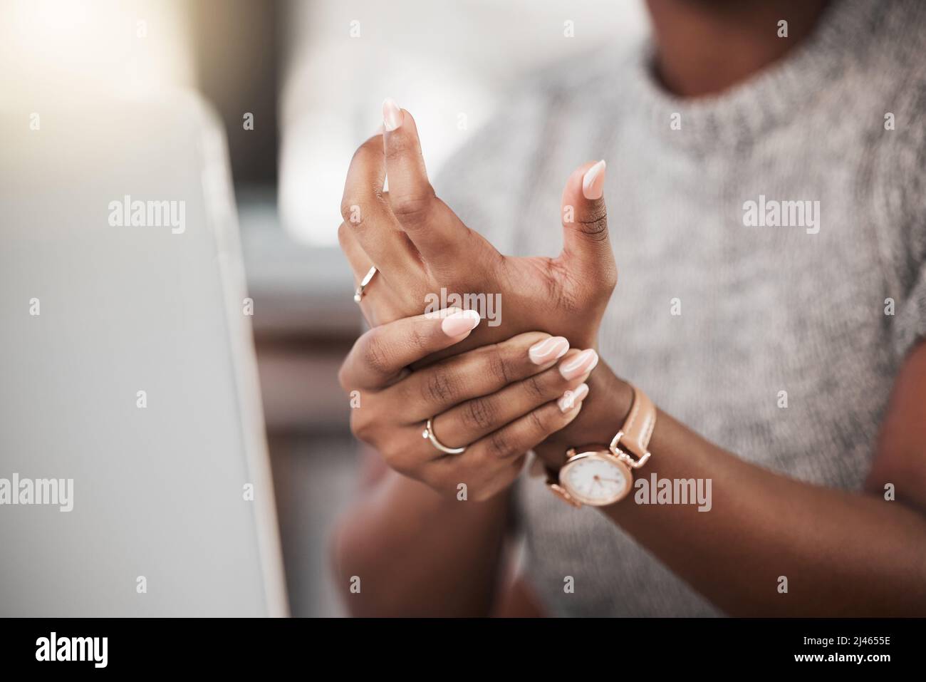 Too much typing is taking its toll. Shot of a businesswoman experiencing wrist pain while using a laptop in a modern office. Stock Photo