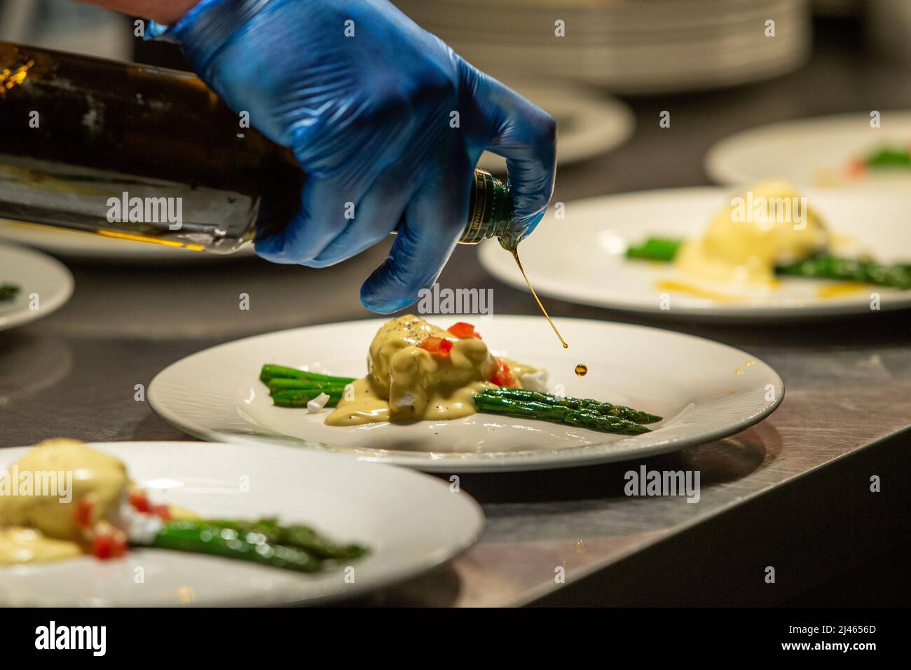 Olive oil being drizzled on gourmet food during plating up. Stock Photo