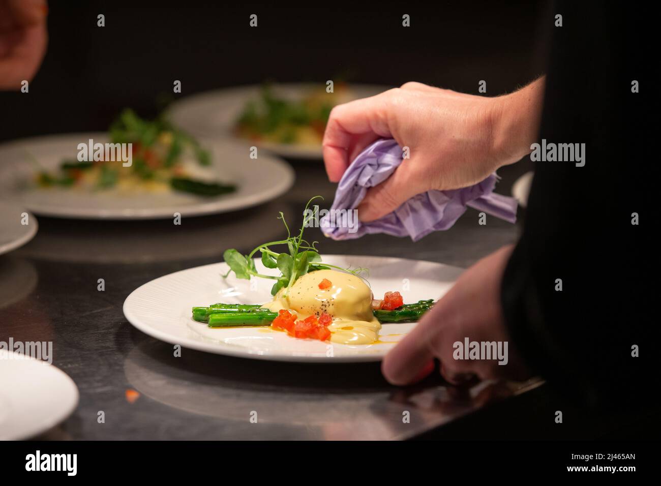 Plate of gourmet food being wiped for presentation before being served Stock Photo
