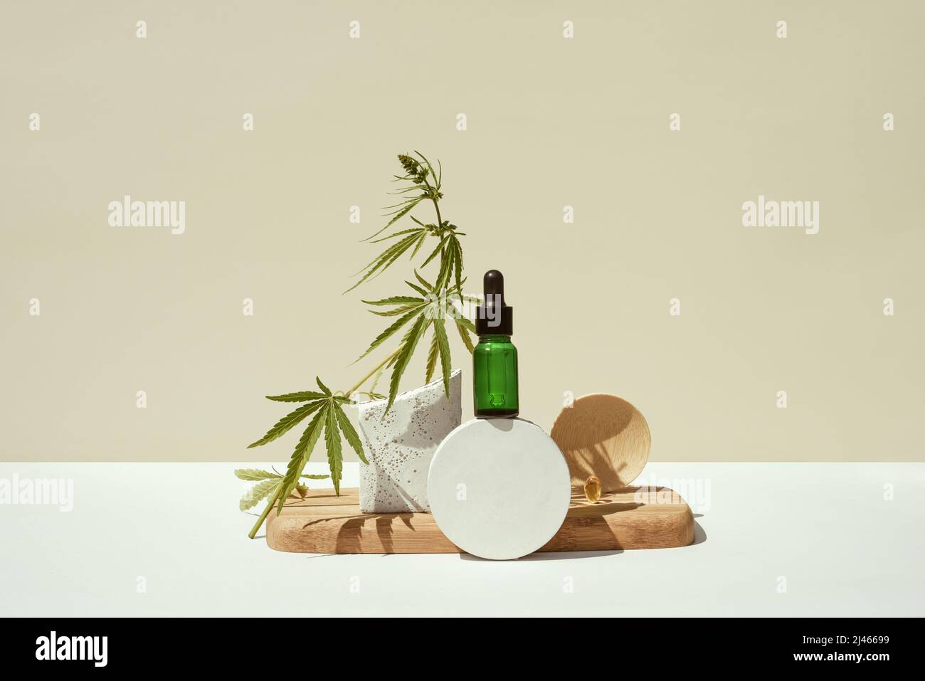 CBD oil in bottle and cannabis bush, hemp in a still life on a geometric and wooden podium. Minimalistic concept of products with cannabidiol on prese Stock Photo