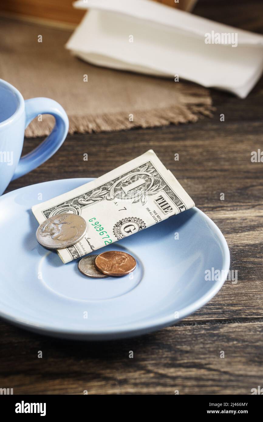 Restaurant tips or gratuity, american banknotes and coins on plate Stock Photo