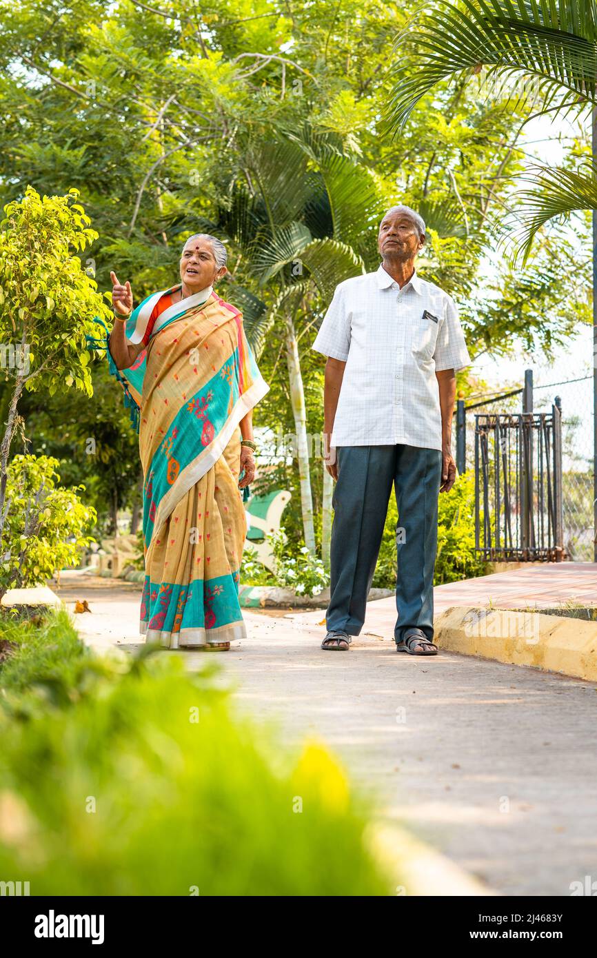 full shot of senior couples walking at garden walking slowly due to knee join pain during morning - conept of togetherness, relationship and healthy Stock Photo