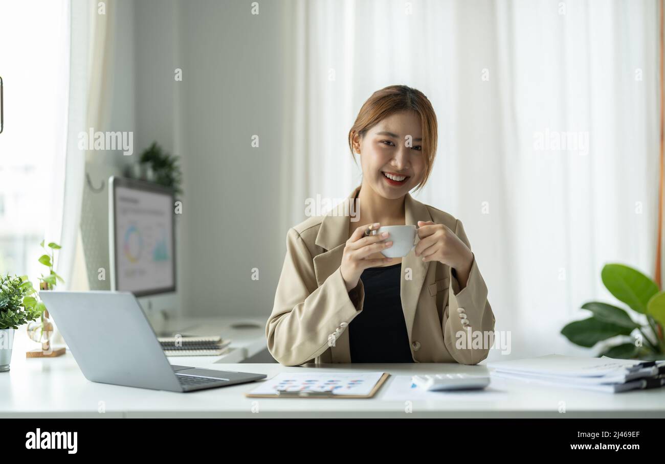Portrait of young beautiful asian businesswoman looking at camera and ...
