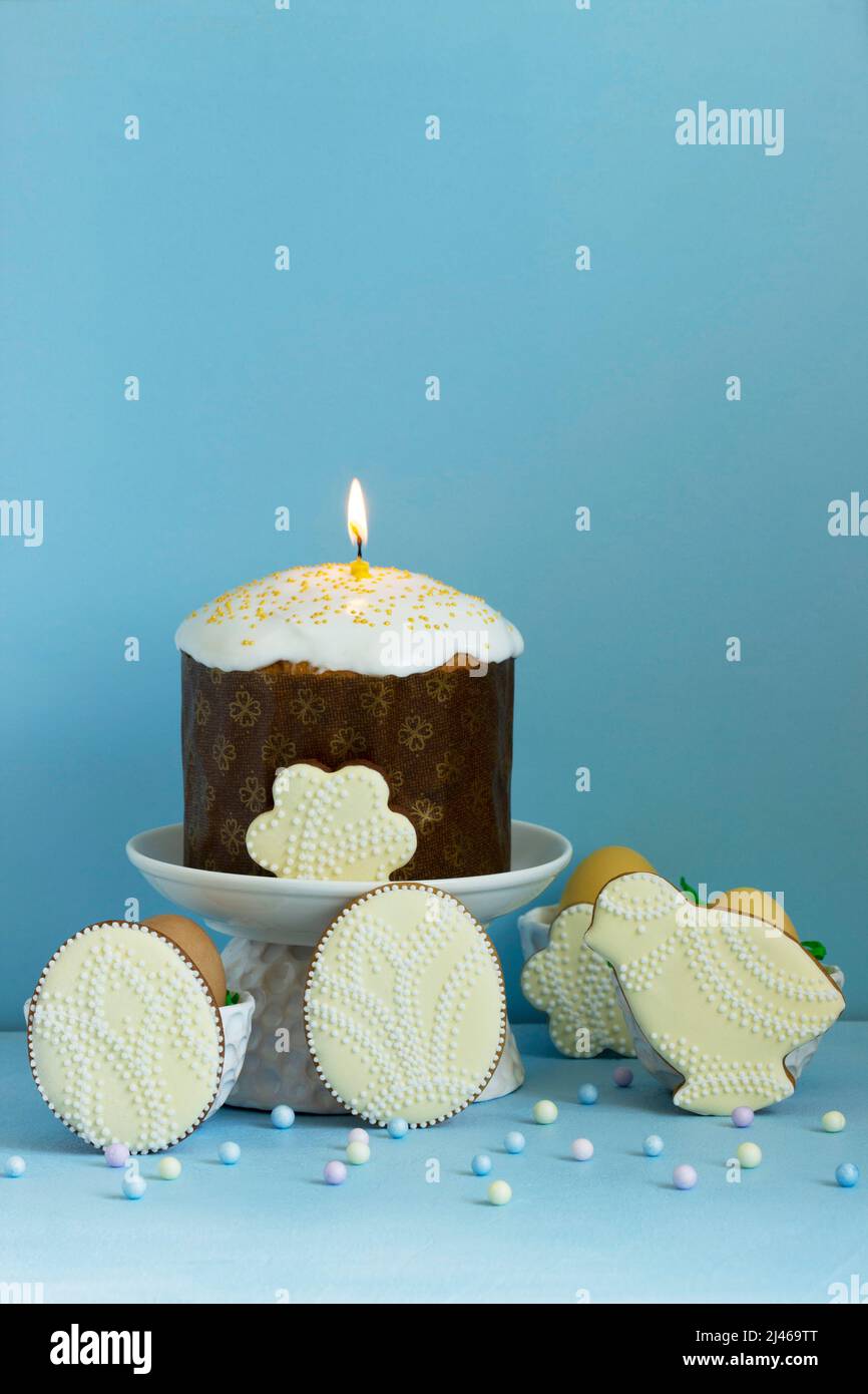 Easter composition, traditional Easter cake, colored eggs and gingerbread on a blue background. Stock Photo