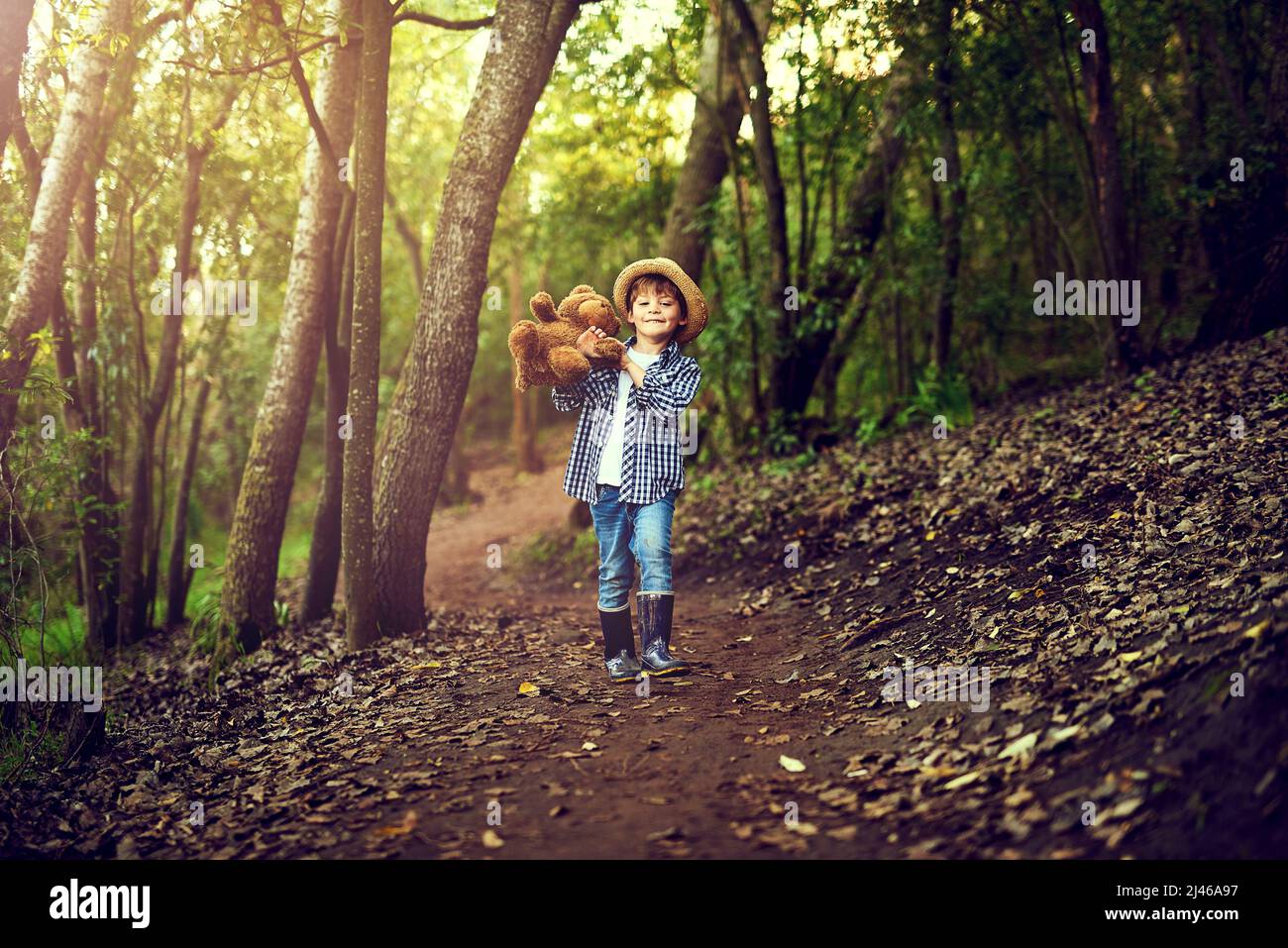 Teddy and I are quite excited about this adventure. Shot of a little boy sitting in the forest with his teddy bear. Stock Photo
