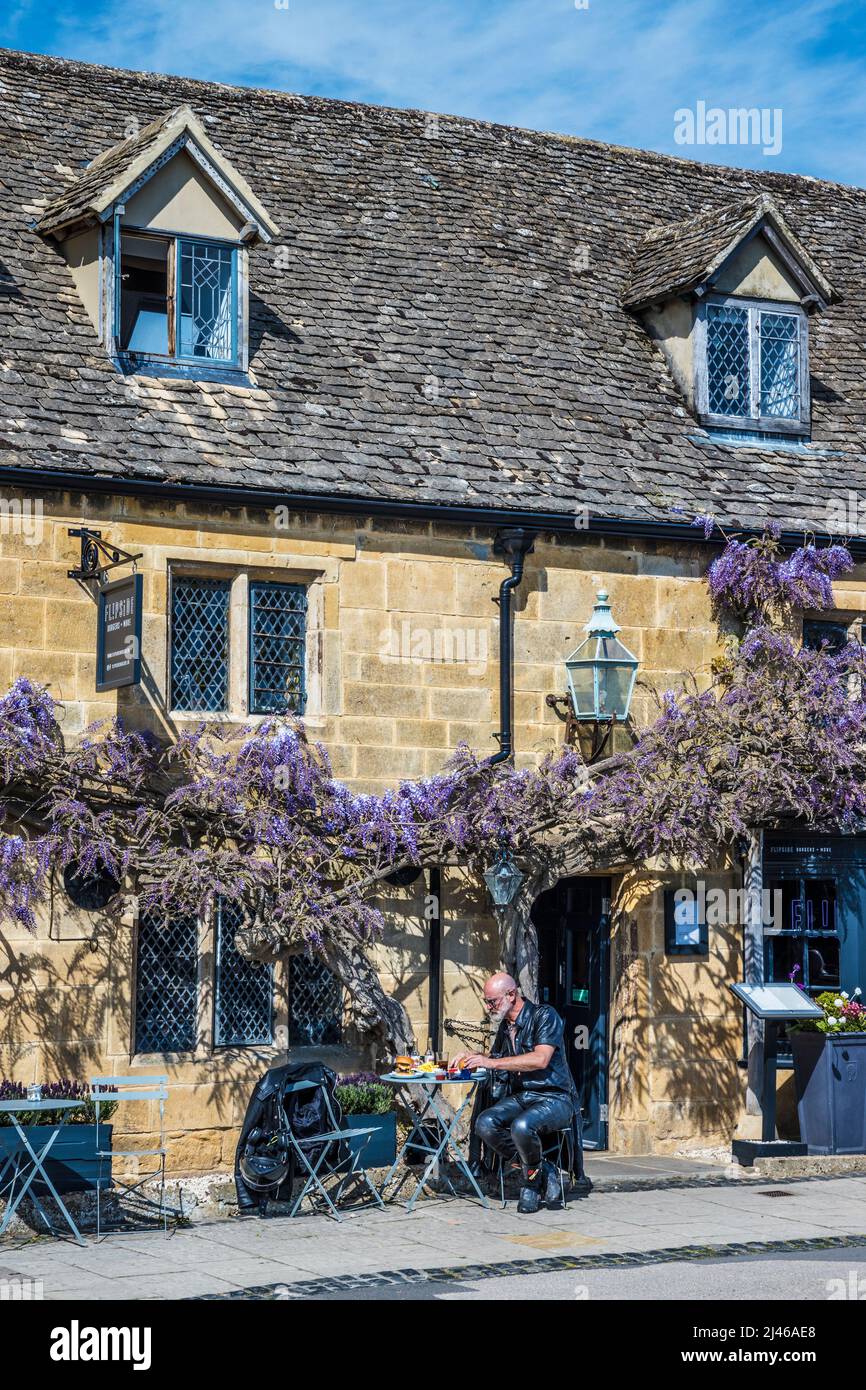 A biker in leathers sitting outside a burger shop in the pretty Cotswold town of Broadway in Worcestershire. Stock Photo