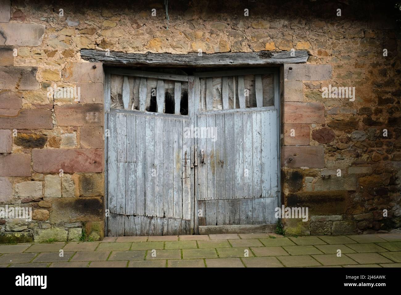 Wooden stable door in stone wall, Cartes, Cantabria, Spain Stock Photo