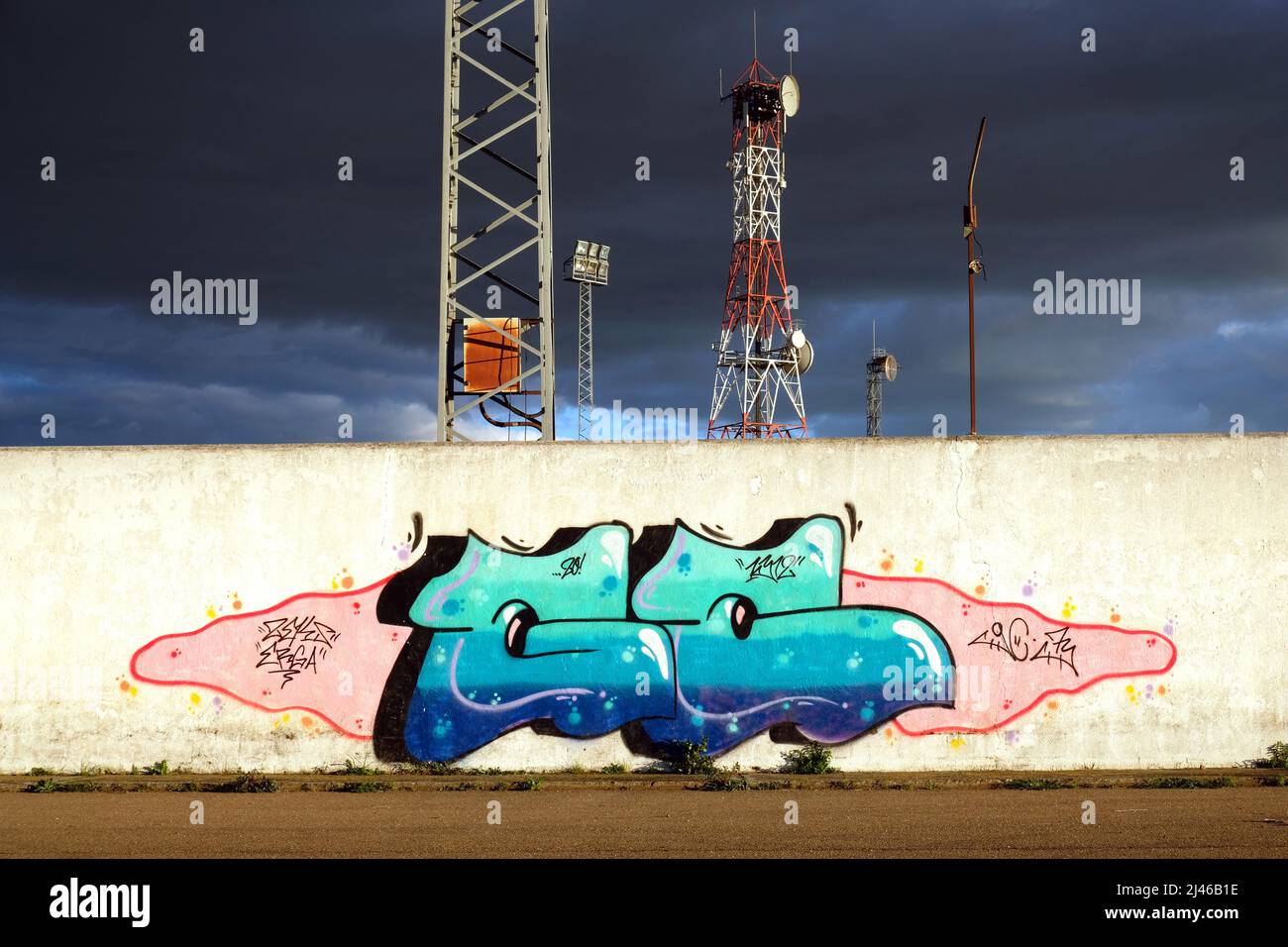 Graffiti on a wall at the football stadium, Orellana la Vieja, Extremadura. Floodlights and aerial towers agains a dark, dramatic sky Stock Photo