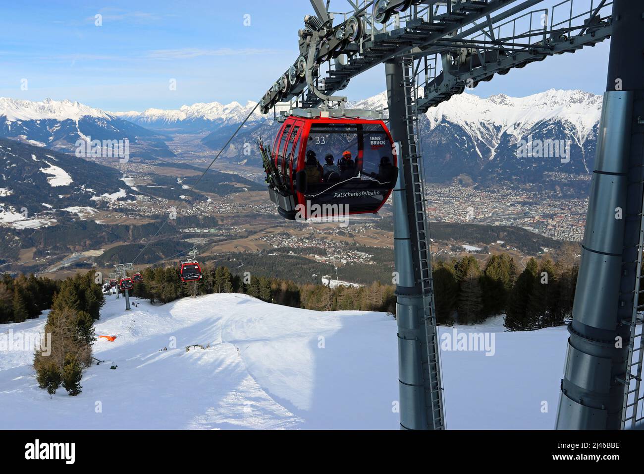 The Patscherkofelbahn cable car approaches the Bergstation; Innsbruck spreads out along the Inn valley below; Nordkette mountain range behind Stock Photo