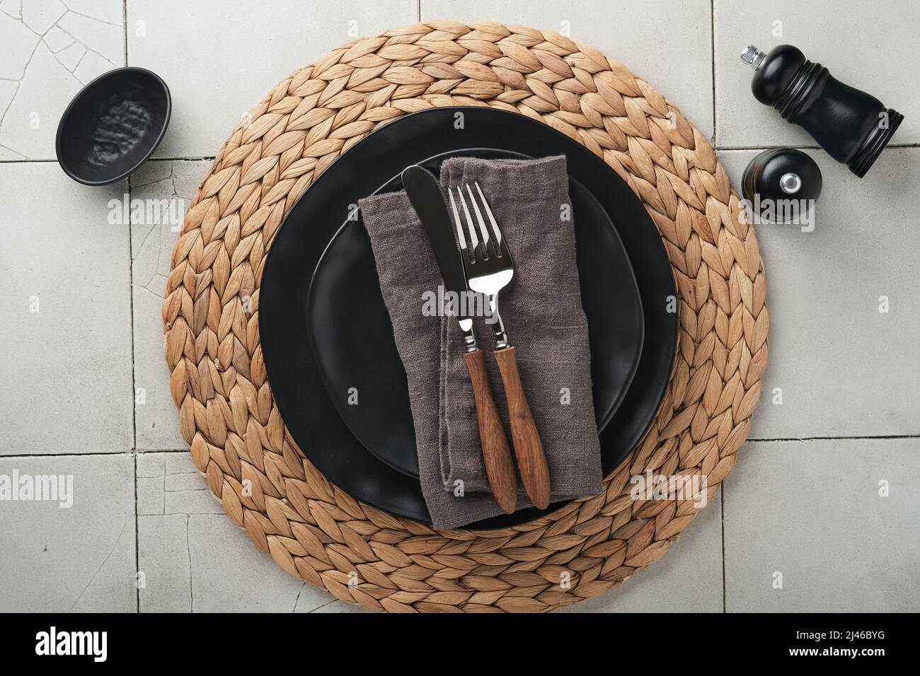 Ceramic empty black plate, silverware and linen kitchen towel napkin on old ceramic tile table background. Cooking stone backdrop. Top view with copy Stock Photo