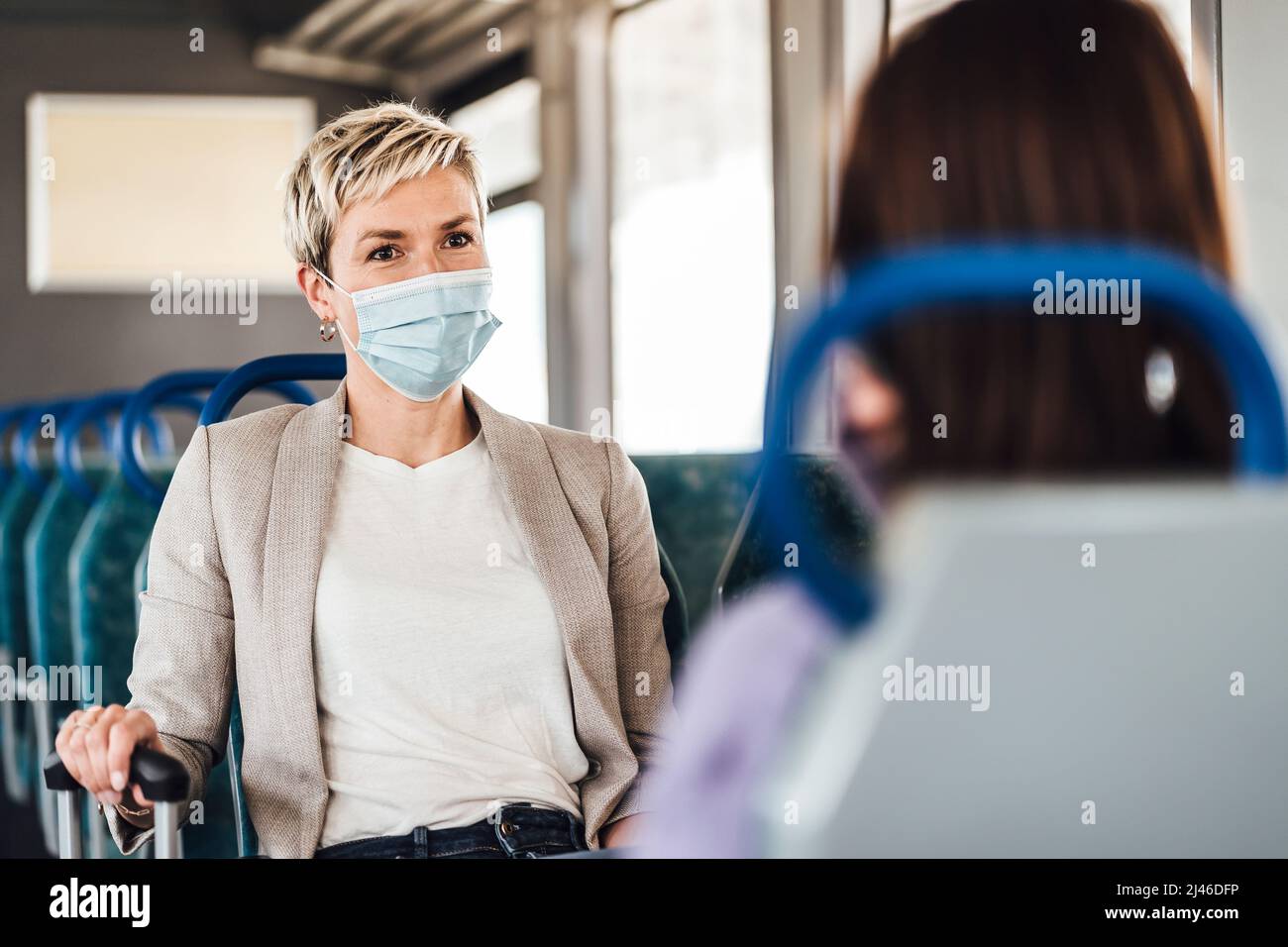 A couple of friends wearing mask and nicely talking while traveling by train Stock Photo