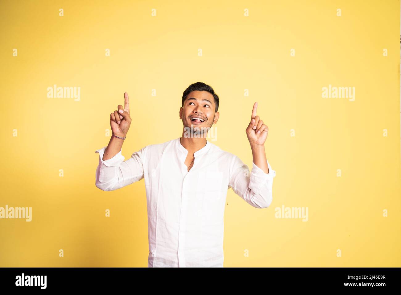 excited asian young man with two fingers pointing up Stock Photo - Alamy