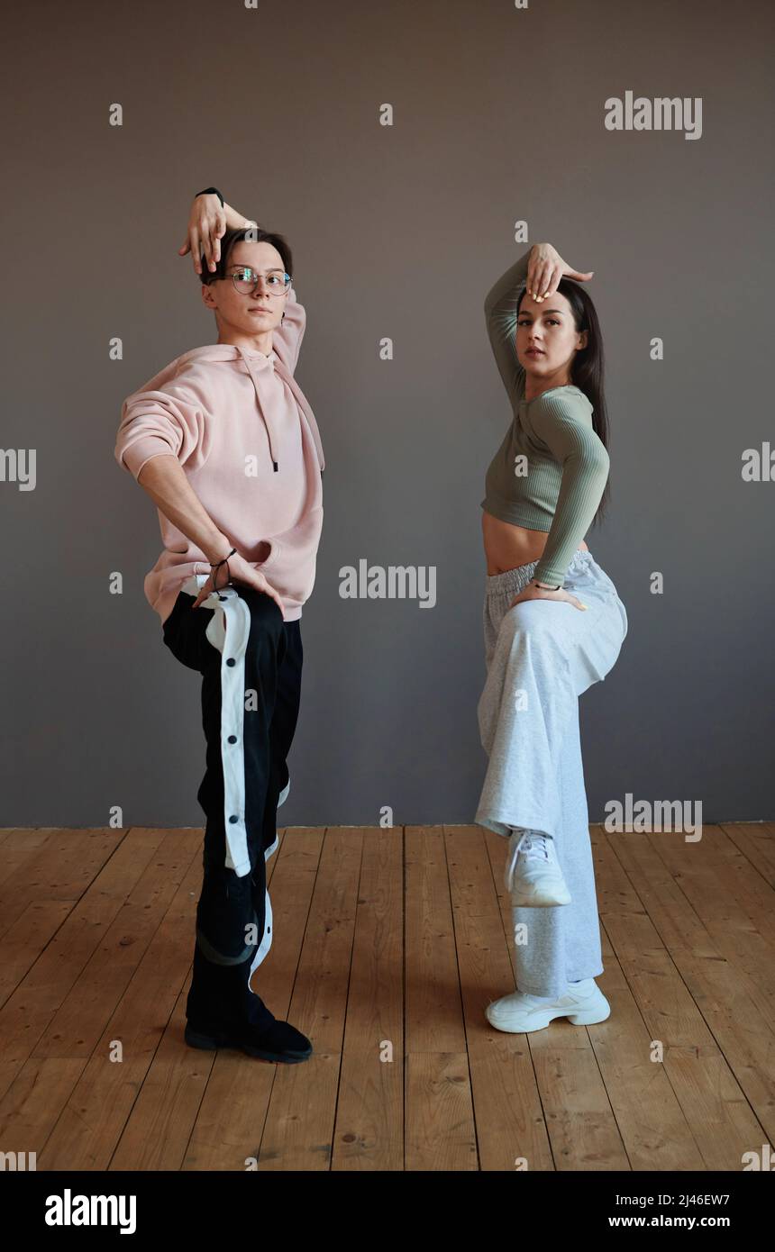 Two youthful vogue dancers in activewear keeping their legs bent in