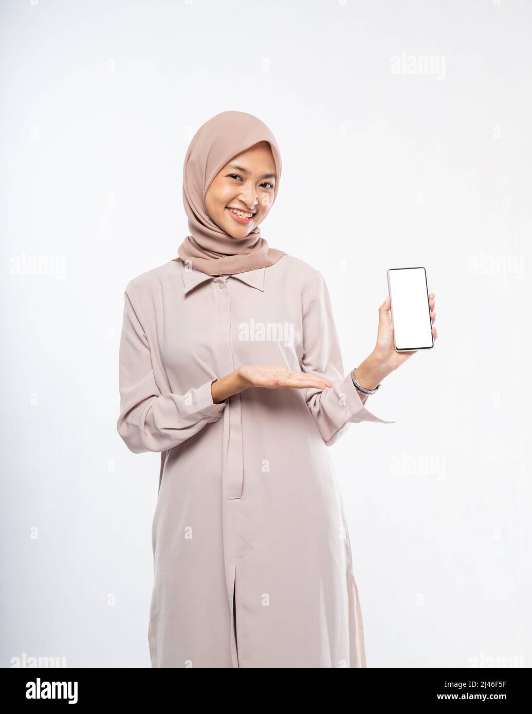 woman in hijab smiling while using a cell phone showing blank screen to ...