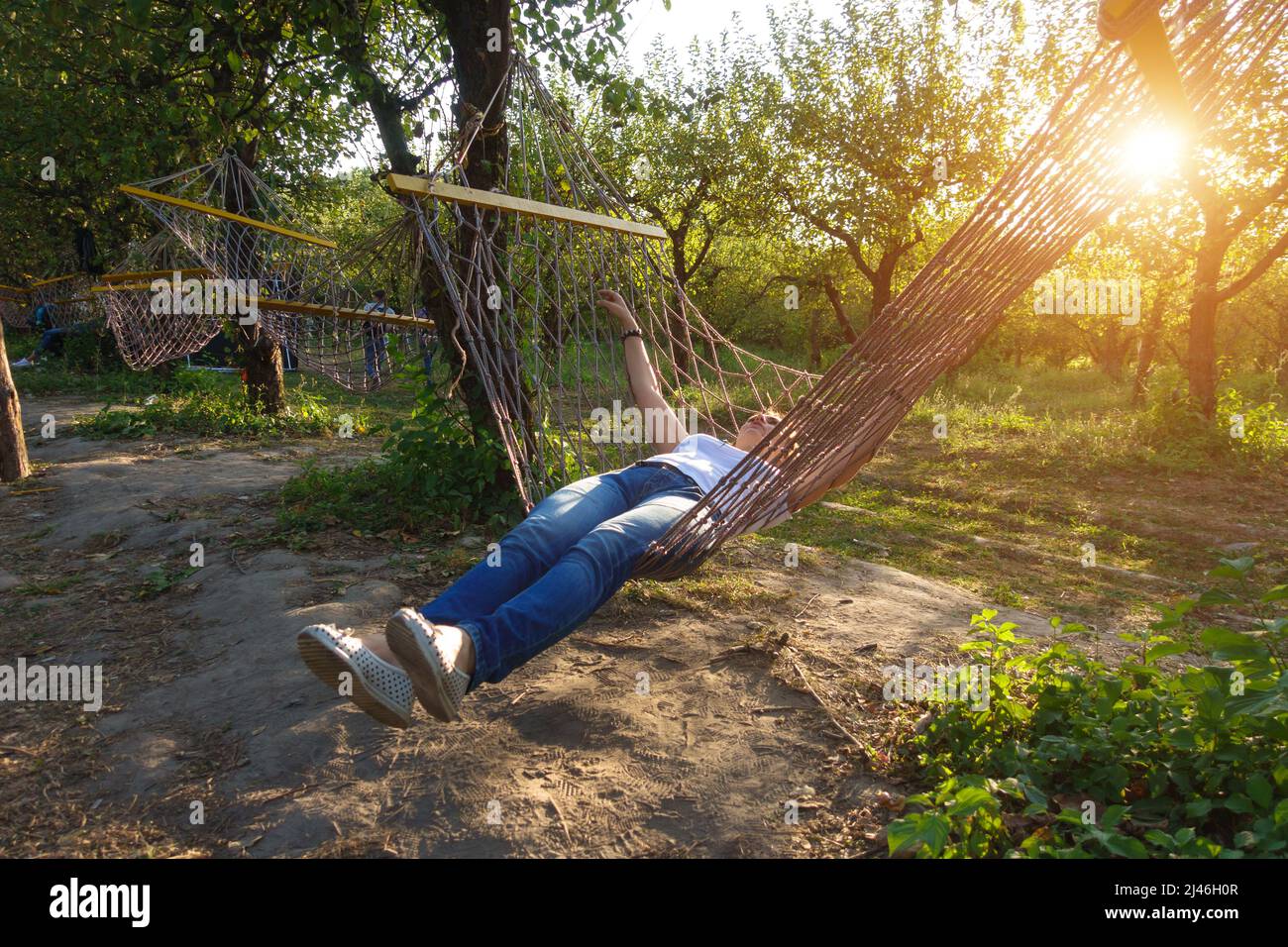 Girl lies on a hammock in the garden. Stock Photo