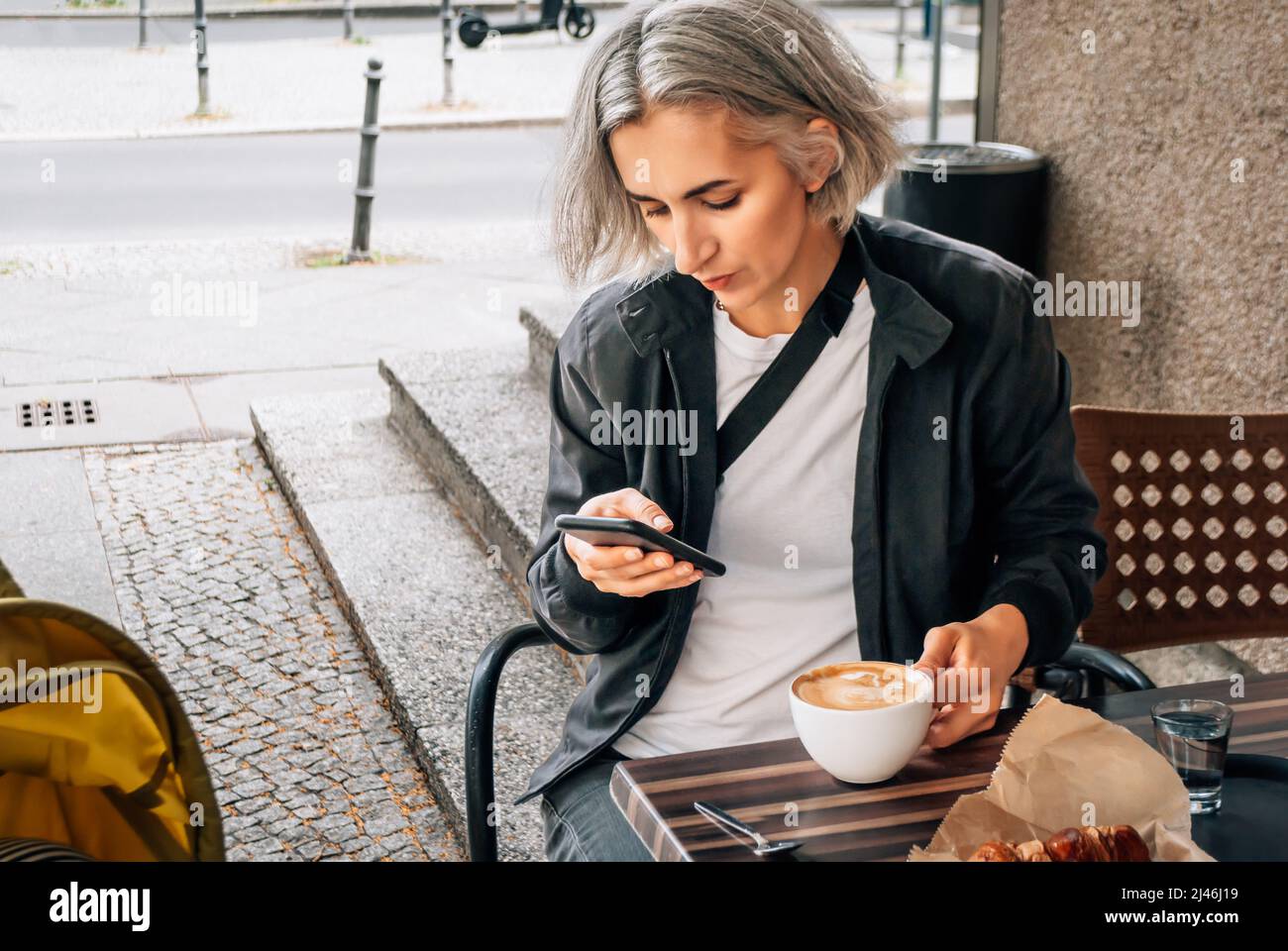 Mother sits at table in street coffee shop near a stroller Stock Photo