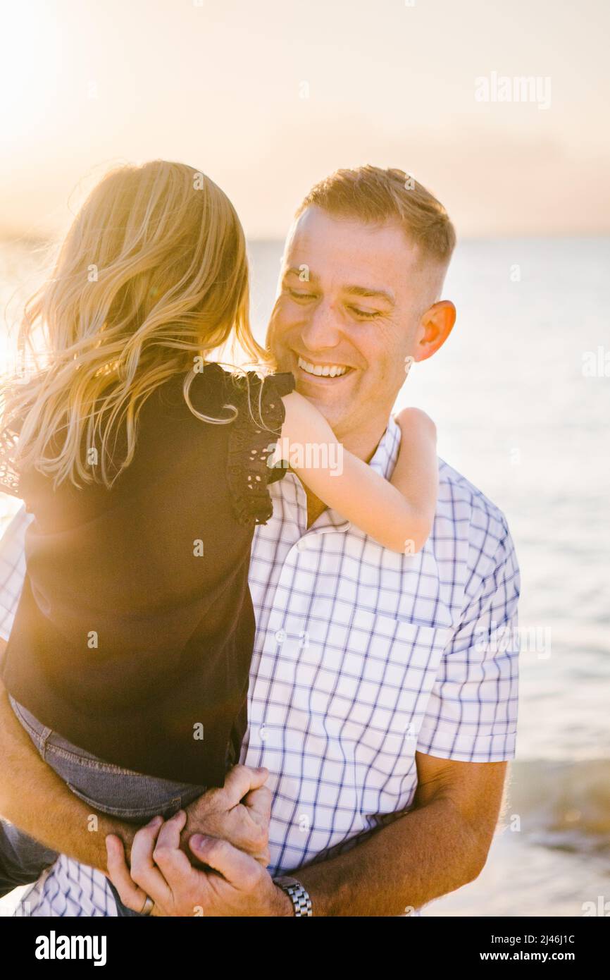 Forty year old father holds five year old daughter laughing on beach ...