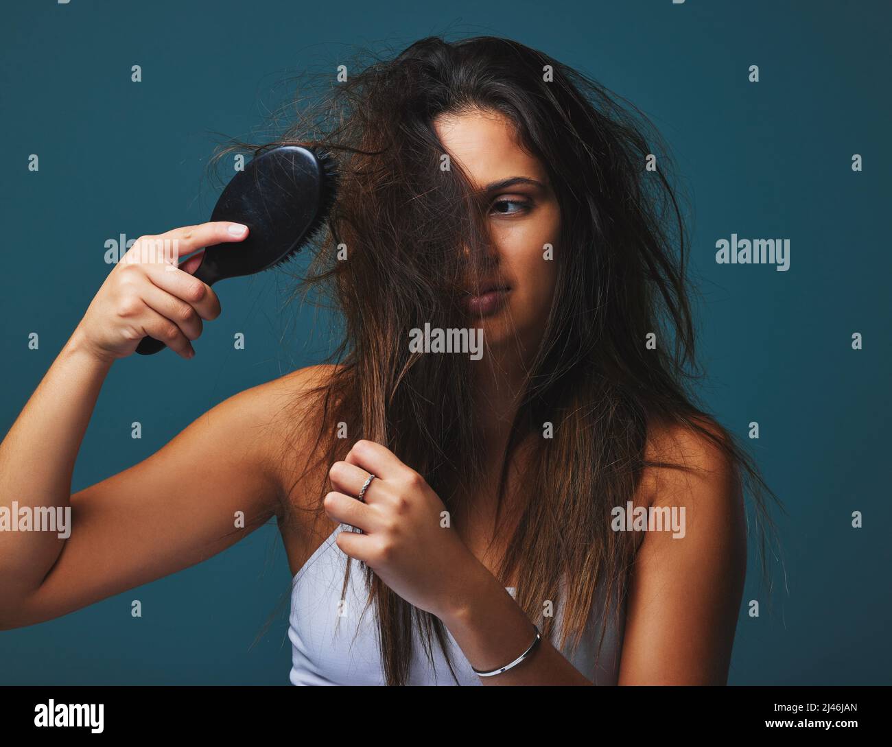 Its not just a hairstyle, its a state of mind. Studio shot of a beautiful young woman holding a brush to her hair posing against a blue background. Stock Photo
