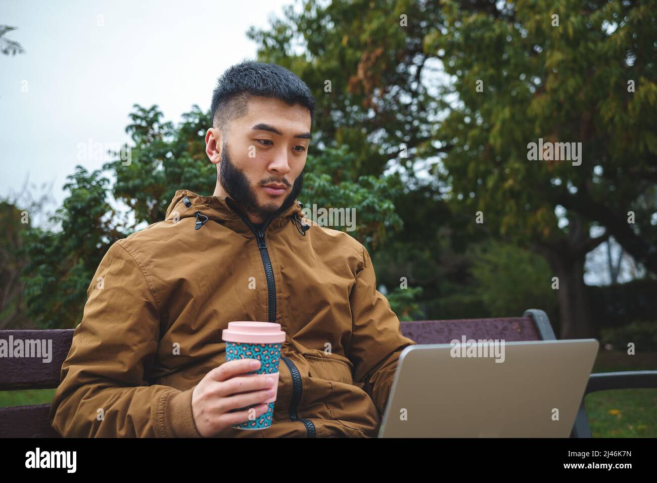 Serious ethnic freelancer working on laptop and drinking coffee Stock Photo