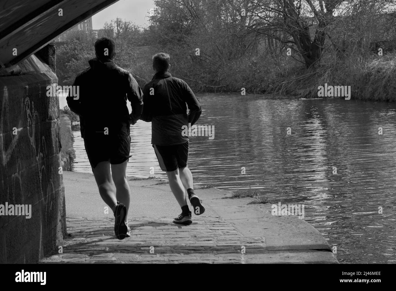 Snapshot of two guys out for a jog along the towpath that parallels the Leeds and Liverpool Canal in Leeds, West Yorkshire, England, UK. Stock Photo