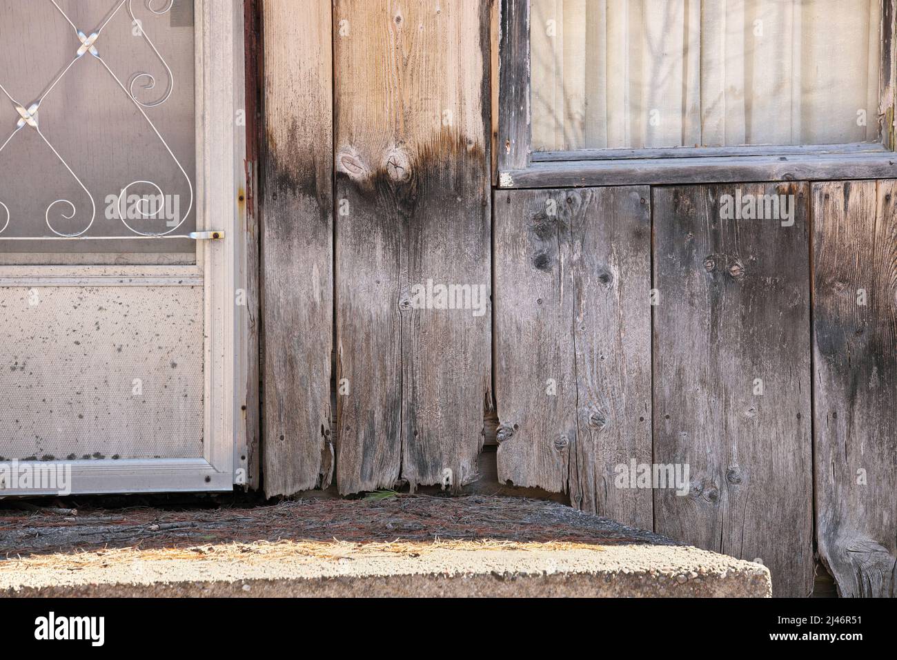 Close up of Weathered Wood Siding Beginning to Rot Around Front Step of Cottage or House Stock