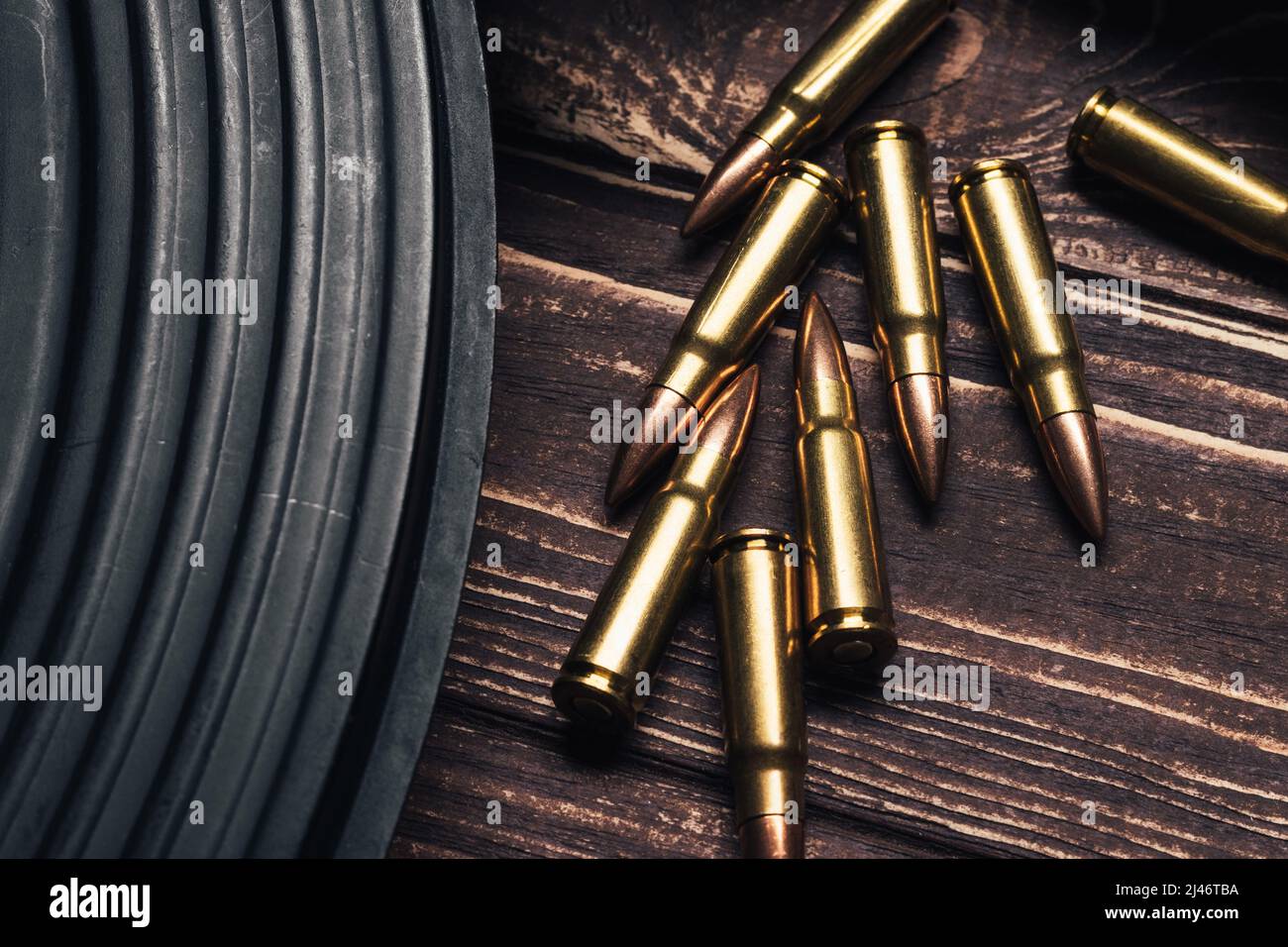 Bullets and Kalashnikov assault rifle on wooden background. Cartridges 7.62 caliber for ak 47 closeup. Selective focus Stock Photo