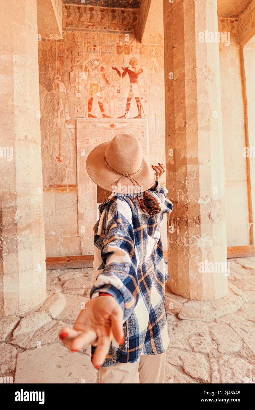 Follow me, happy woman traveler to the ruins of the ancient egyptian Hatshepsut temple in the heritage city of Luxor. Columns with painted hieroglyph Stock Photo