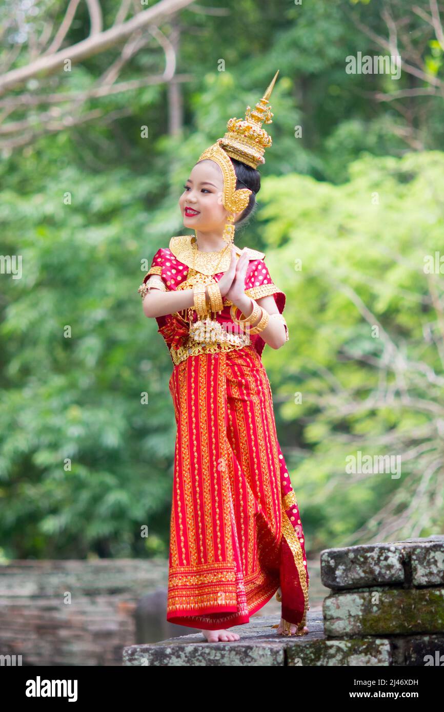 Asian woman wearing typical, traditional Thai Dress standing on an antique  stone ladder. Red and gold National costume Stock Photo - Alamy