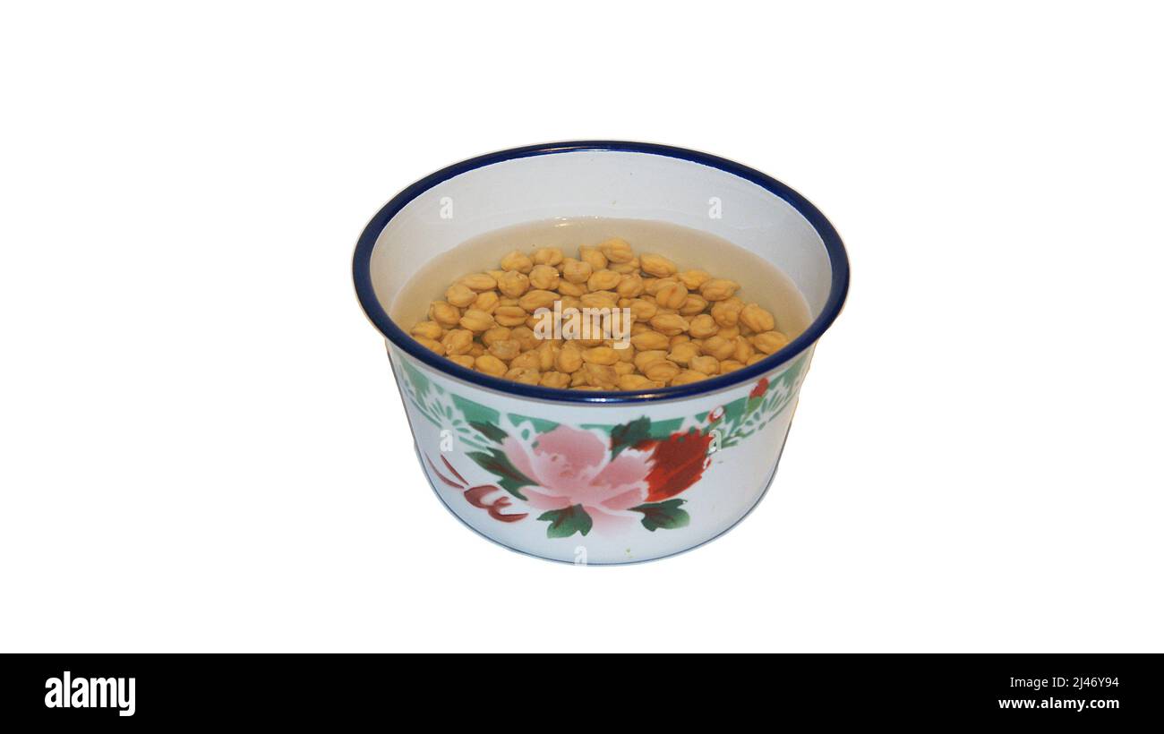 Chickpeas soaking in a porcelain bowl on white background Stock Photo