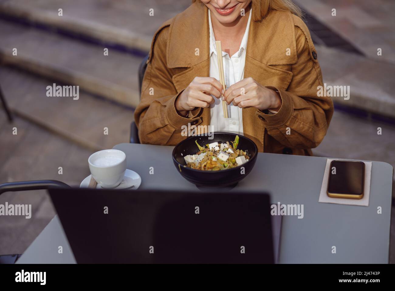 Portrait of woman sitting in cafe, holding chopsticks Stock Photo