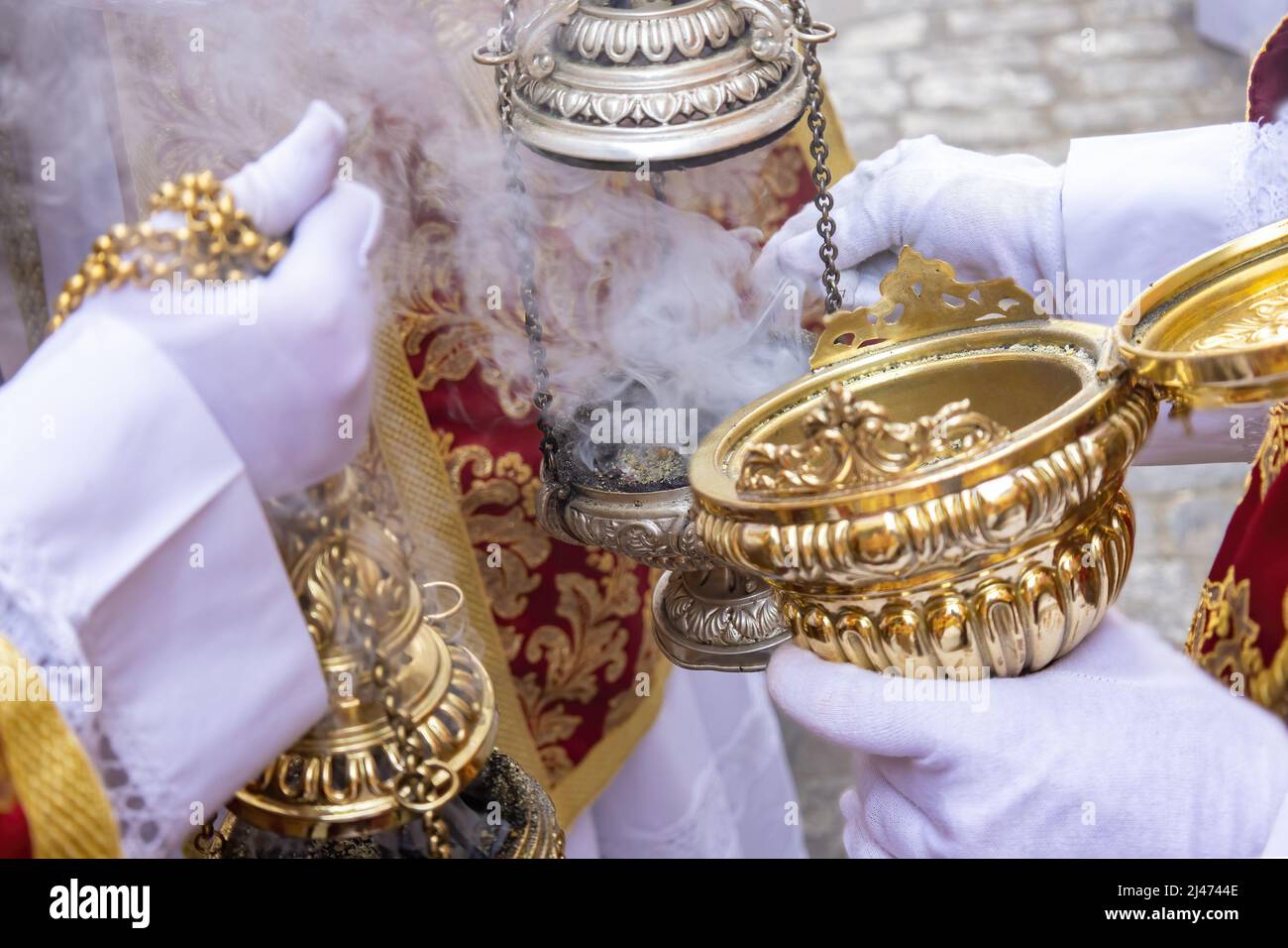 Altar boy or acolyte in the holy week procession shaking a ...