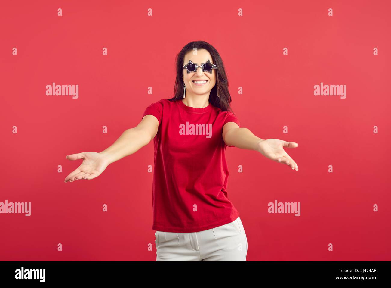 Close up portrait of stylish beautiful woman going to rock concert wearing glasses in the form of stars. Cool mood. Isolated on red background. Stock Photo