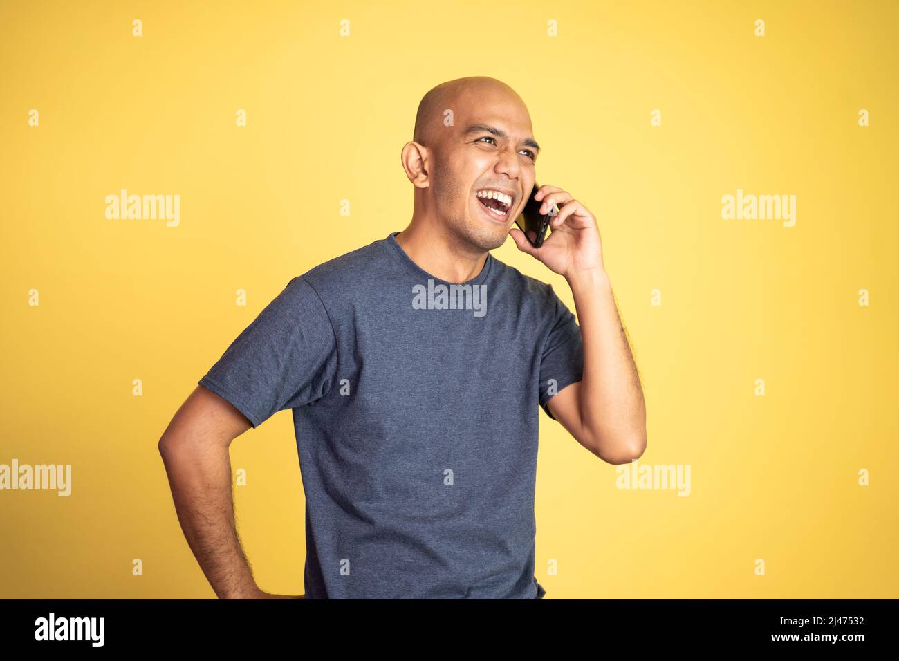 bald man laughing while making phone call Stock Photo
