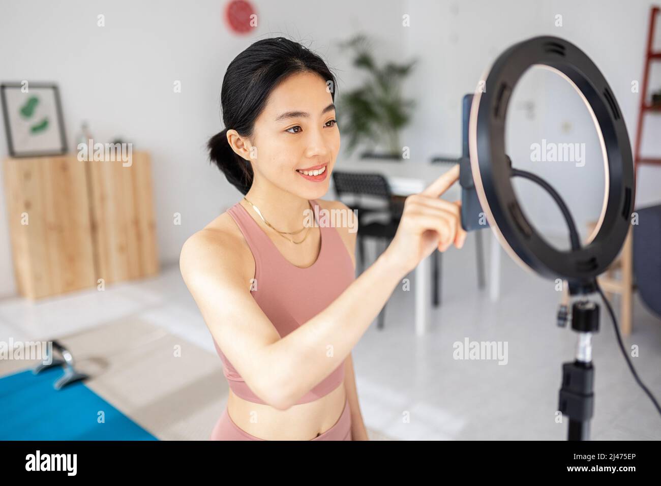 Female trainer preparing an streaming fitness video class from home Stock Photo
