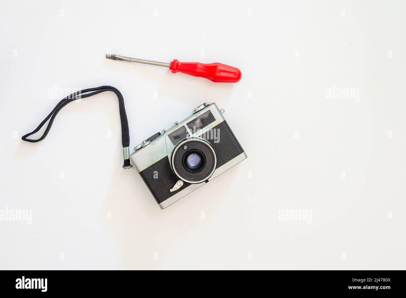 Old film photo camera and a screwdriver on a white background. Salvador, Bahia, Brazil. Stock Photo