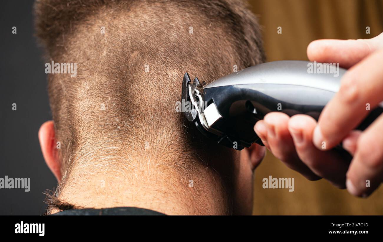 cutting hair with a trimmer hairdresser shaves hair Stock Photo