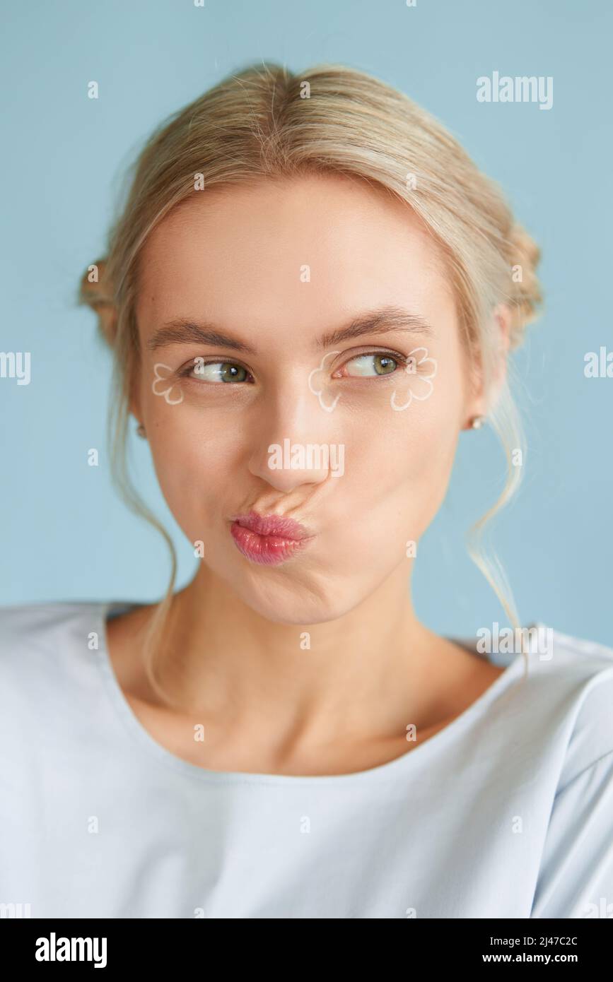 Young hipster blonde woman with trendy make-up cute smiling. Natural emotions. Blue background Stock Photo