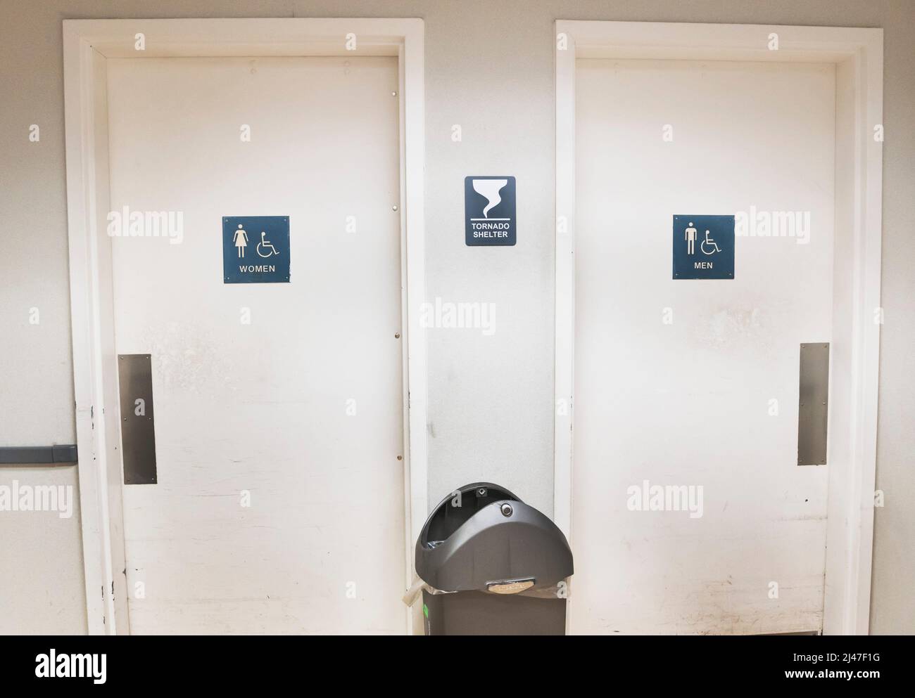 A Tornado Shelter sign between a men's and women's bathroom doors inside a retail store in North Central Florida. Stock Photo