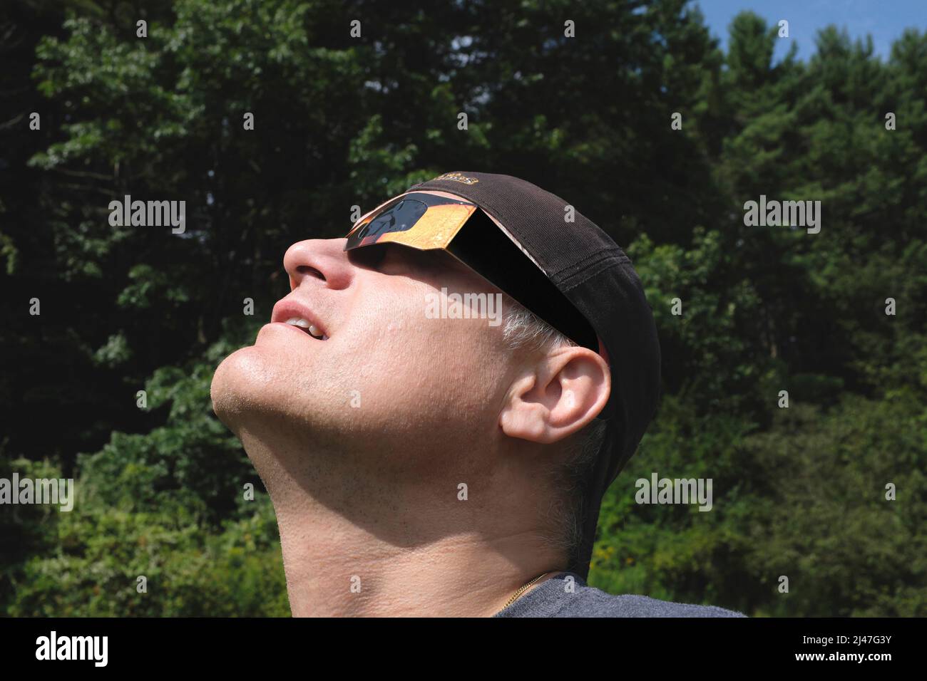 Mid-Adult Man wearing Eclipse Glasses while viewing Partial Solar Eclipse Stock Photo