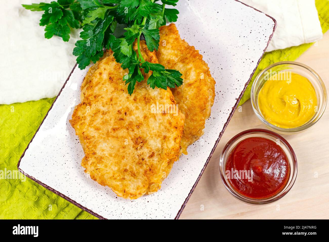 Top view of roasted meat in breading with cheese  and different sauces for dinner. Stock Photo