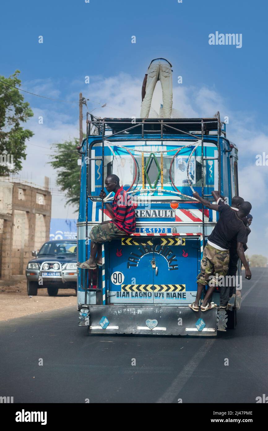 Senegal, Highway Safety.  Passengers Riding on end of bus, or on top.  No seat belts here! Stock Photo
