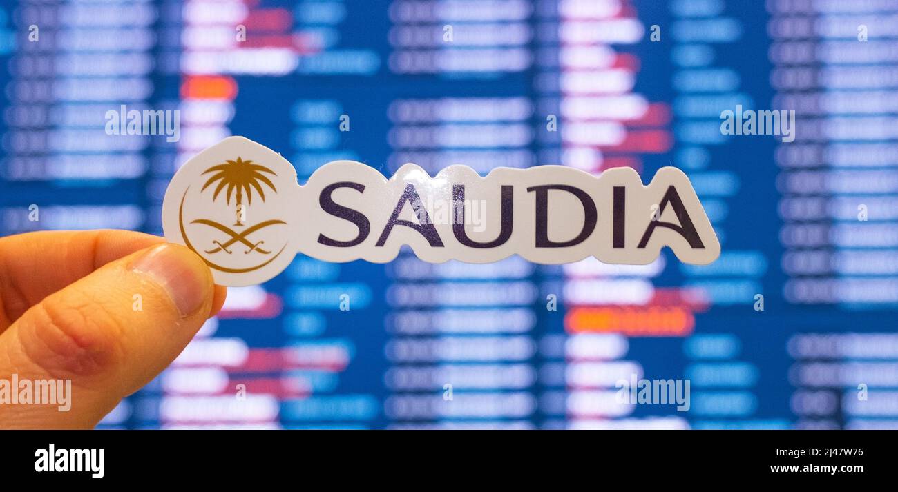 December 11, 2021, Jeddah, Saudi Arabia. The emblem of the Saudia airline against the background of an electronic board with a flight schedule at the Stock Photo