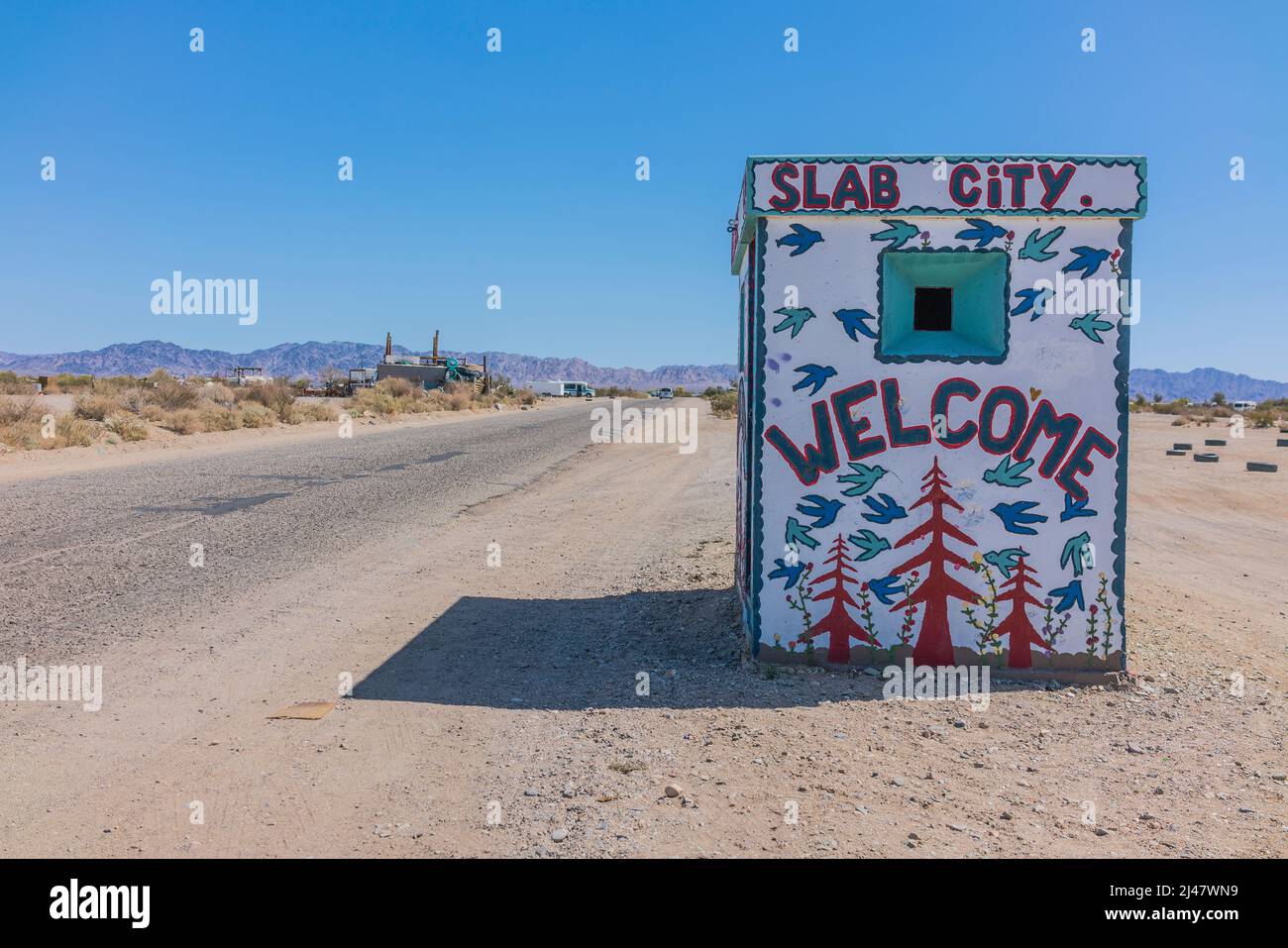 A tiny building with a mural painted on it welcoming visitors to Slab City. It is an off-the-grid community with no municipal services. It gets it nam Stock Photo