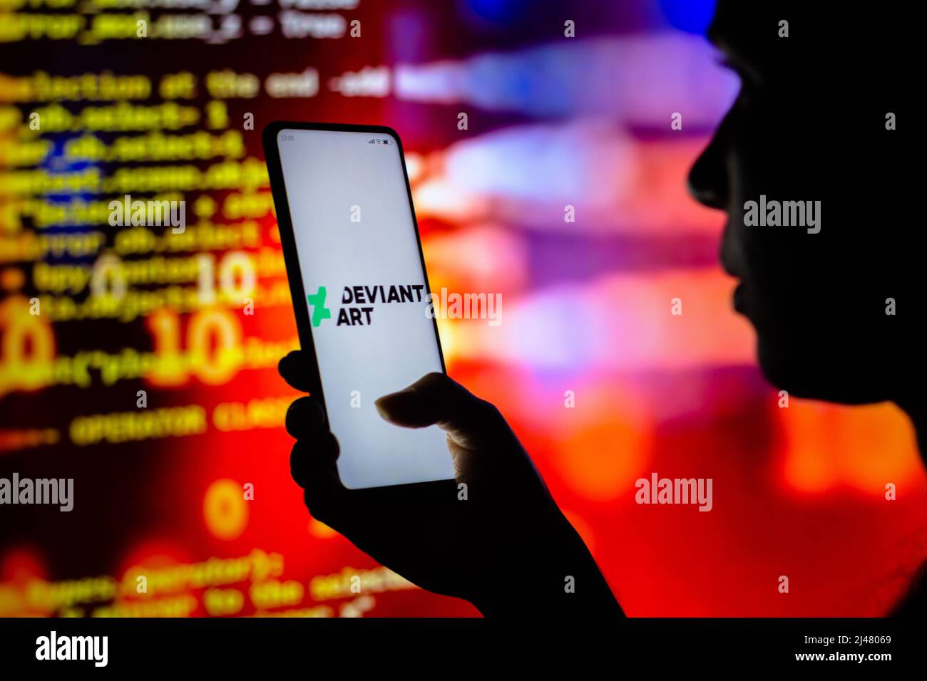 In this photo illustration, a woman holds a smartphone with the DeviantArt logo displayed on the screen. Stock Photo