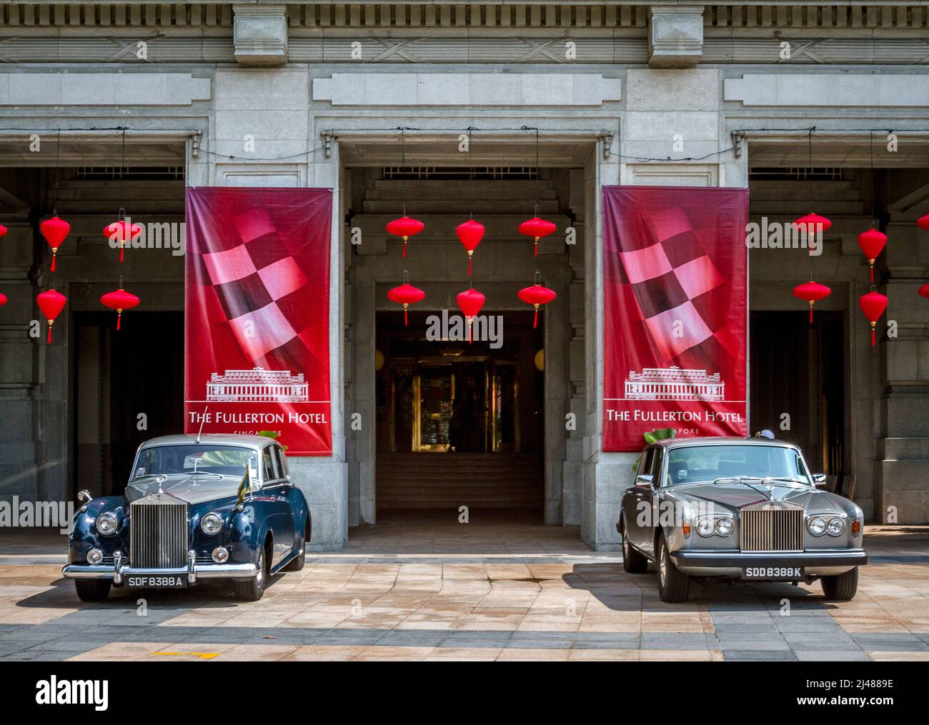 Two Rolls Royce luxury cars sit in front of the Fullerton Hotel in Singapore. Stock Photo