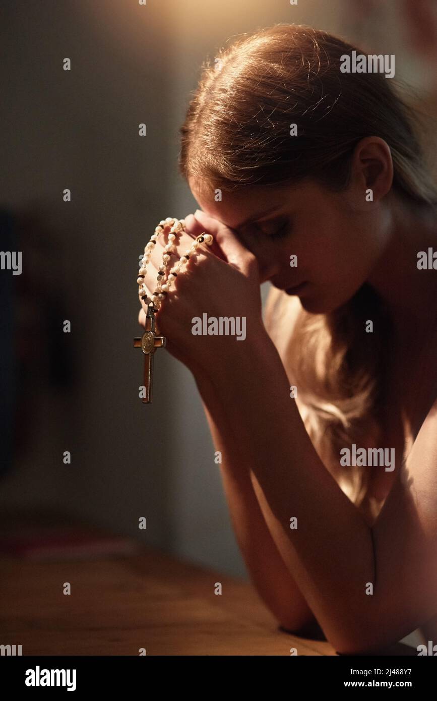 Seeking advice from above. Cropped shot of a young woman praying in a church. Stock Photo