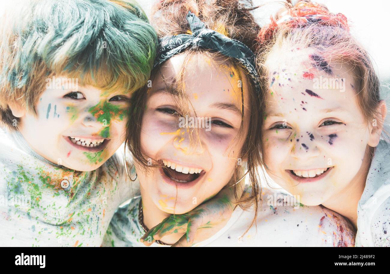 Close up portrait of happy excited litttle kids on holi color festival. Cute children with colorful paint powder on faces. Stock Photo